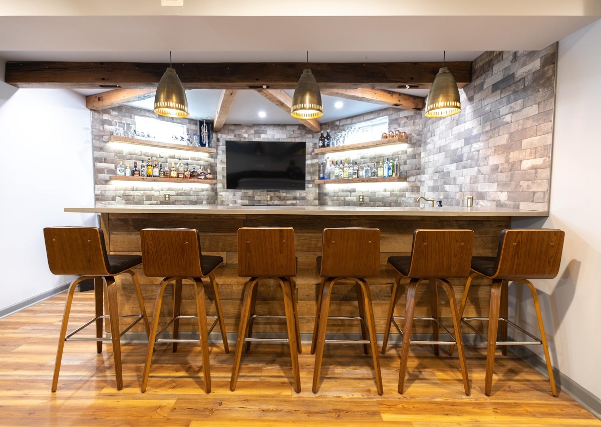 Basement remodeling in Northern Virginia featuring a custom home bar, wood accents, built-in shelving, and seating area designed to add livable square footage and functional entertainment space in the DC area.