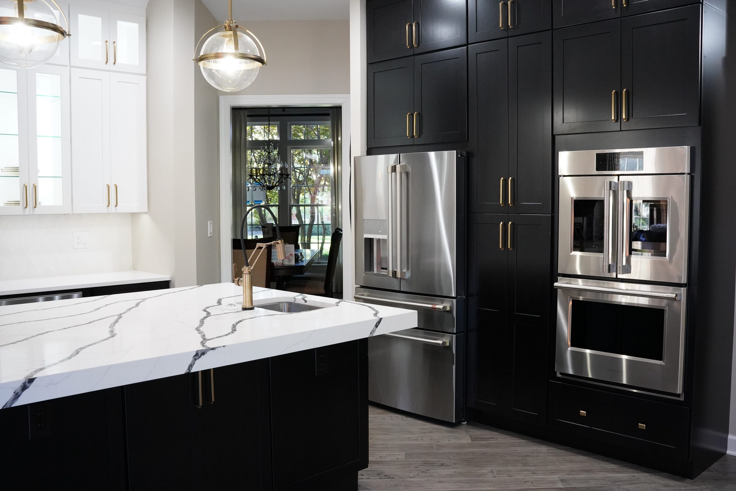Modern kitchen with a white quartz waterfall island featuring bold gray veining, black cabinetry, and stainless steel appliances