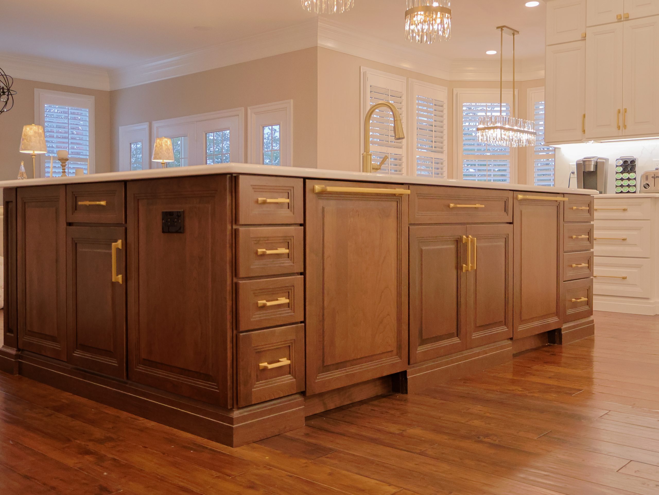 Kitchen featuring floor-standing wood cabinets with brass hardware, a large center island, and hardwood flooring as part of 2026 interior decor ideas for kitchen remodeling.