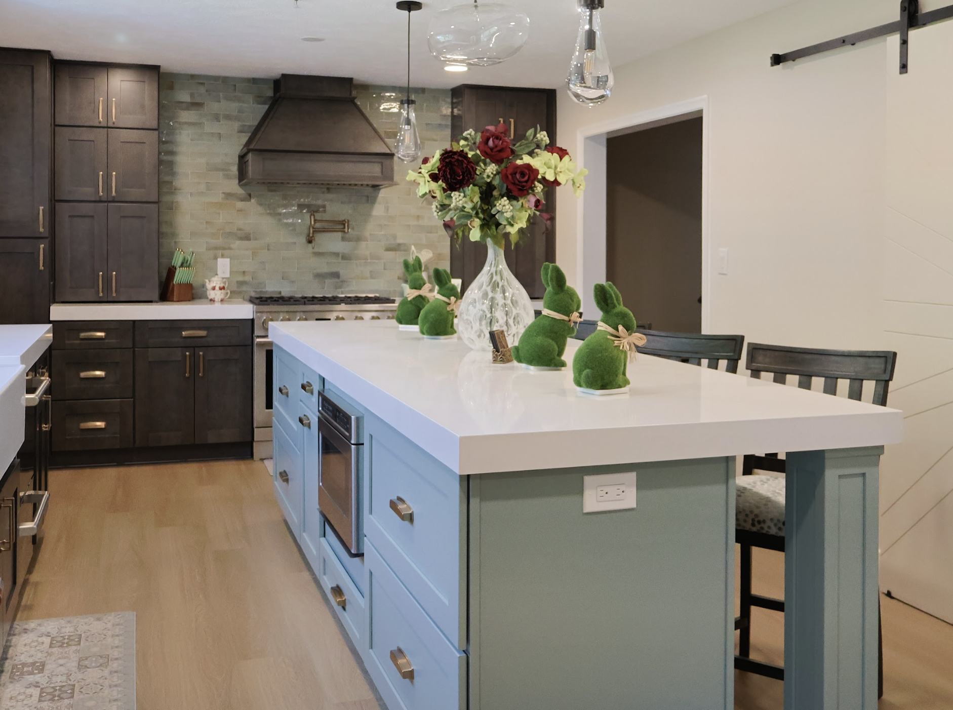 Kitchen with a white quartz countertop island, blue base cabinetry, pendant lighting, and dark wood cabinets highlighting a popular countertop material choice for modern kitchens.