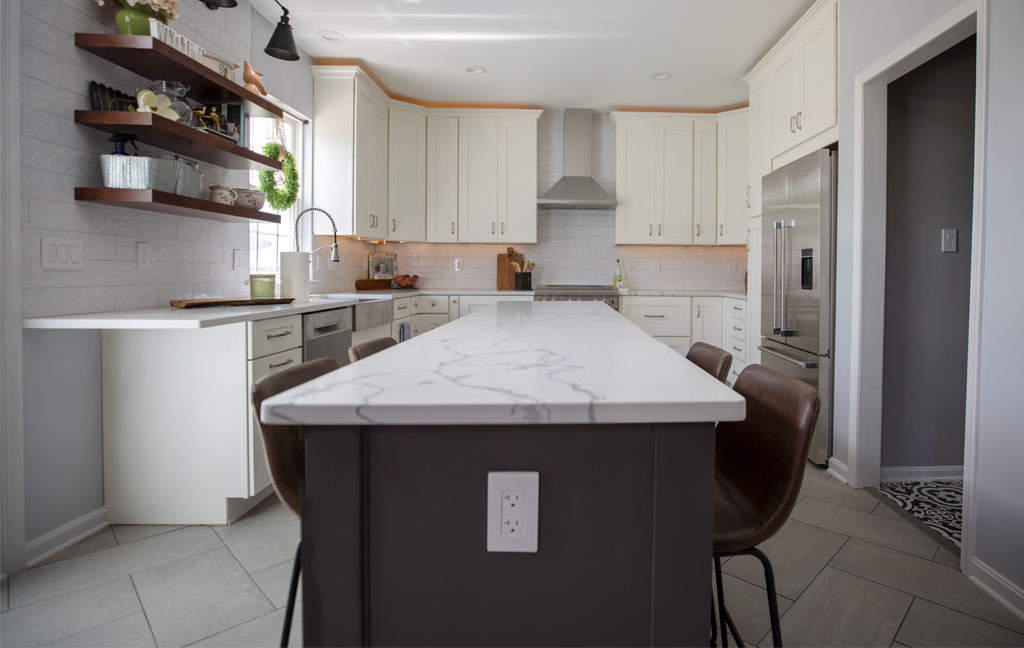 Modern kitchen remodel with a white quartz island featuring gray veining, cream cabinets, stainless steel appliances, and open wood shelving