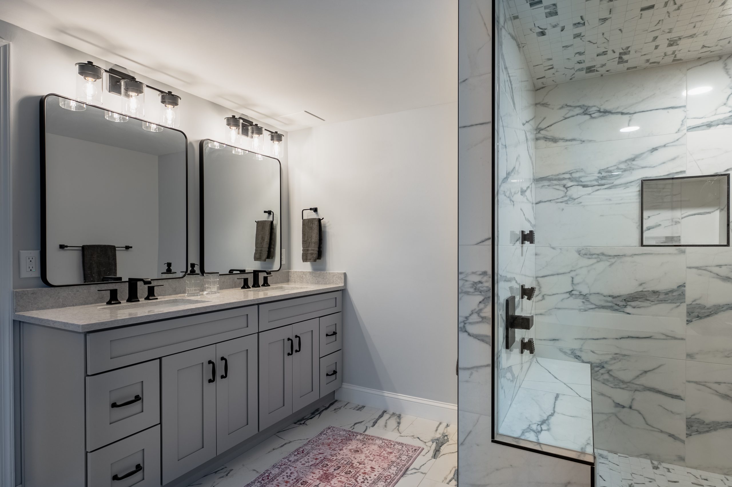 Bathroom remodel with a freestanding oval soaking tub, marble tile walls, and a glass walk-in shower nearby.