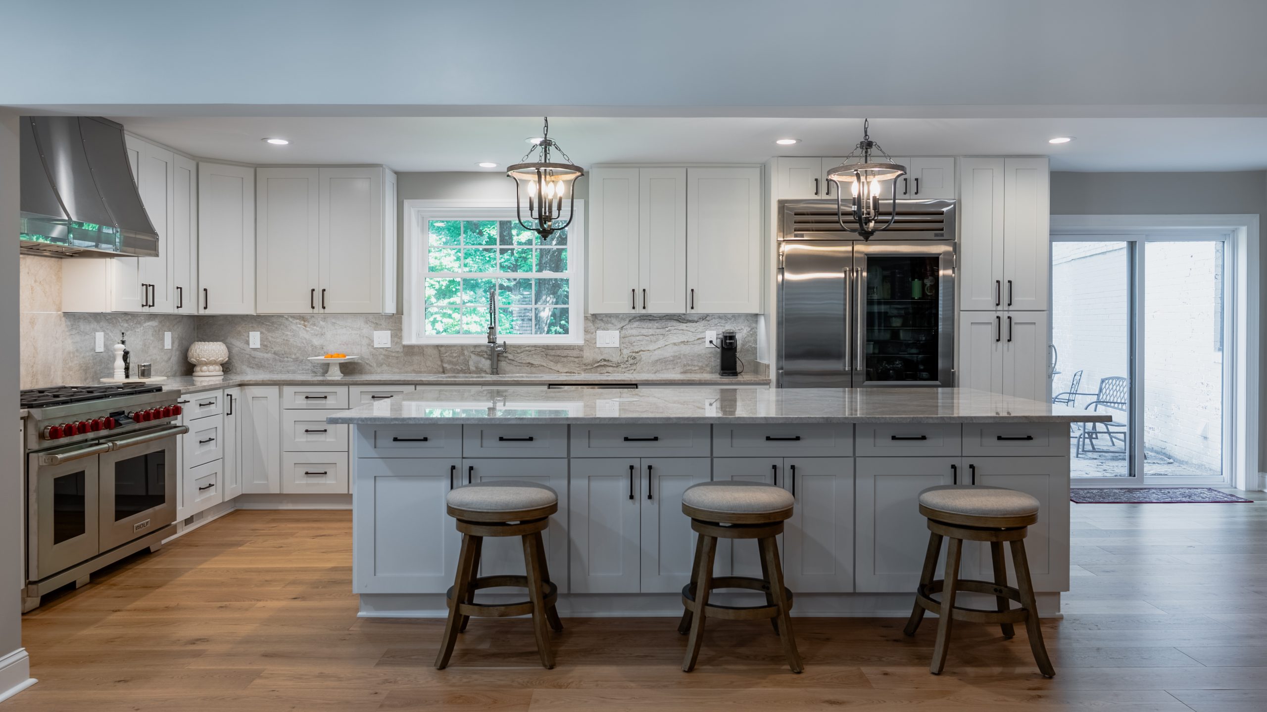 White shaker kitchen remodel in Arlington, VA with a long quartz island, swivel stools, and a Wolf range.