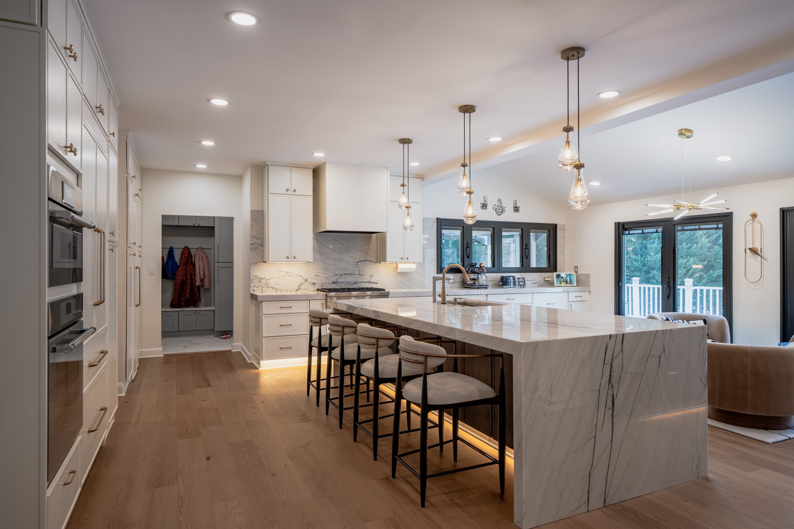 Open white kitchen remodel with a marble waterfall island, bar seating and white oak floors in Fredericksburg, VA