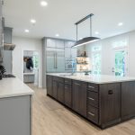 Two-tone kitchen with light gray perimeter cabinets, a dark island, quartz counters, and the mudroom beyond, Leesburg VA