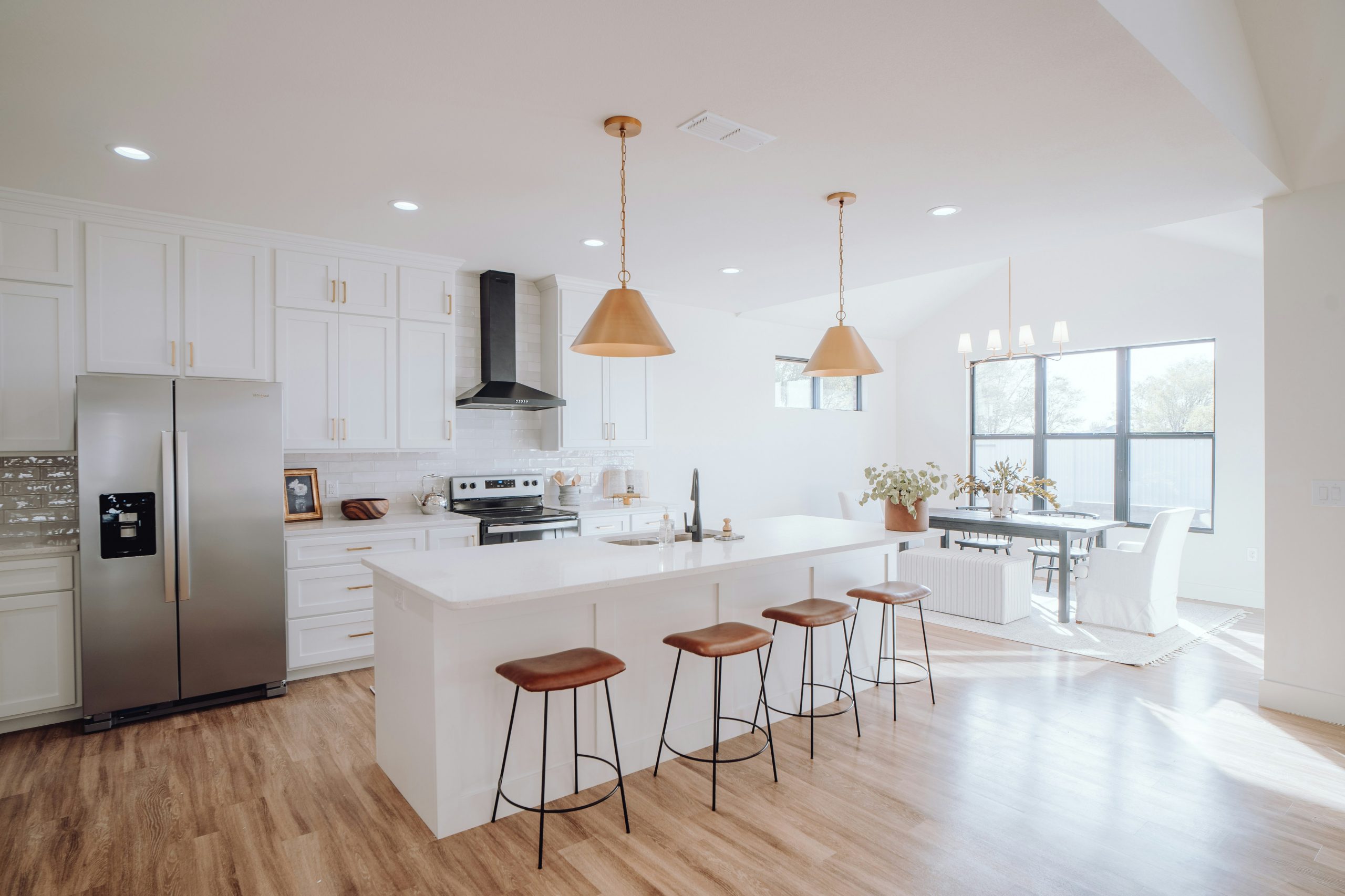 Spacious open kitchen design with light cabinets, large windows, and an island