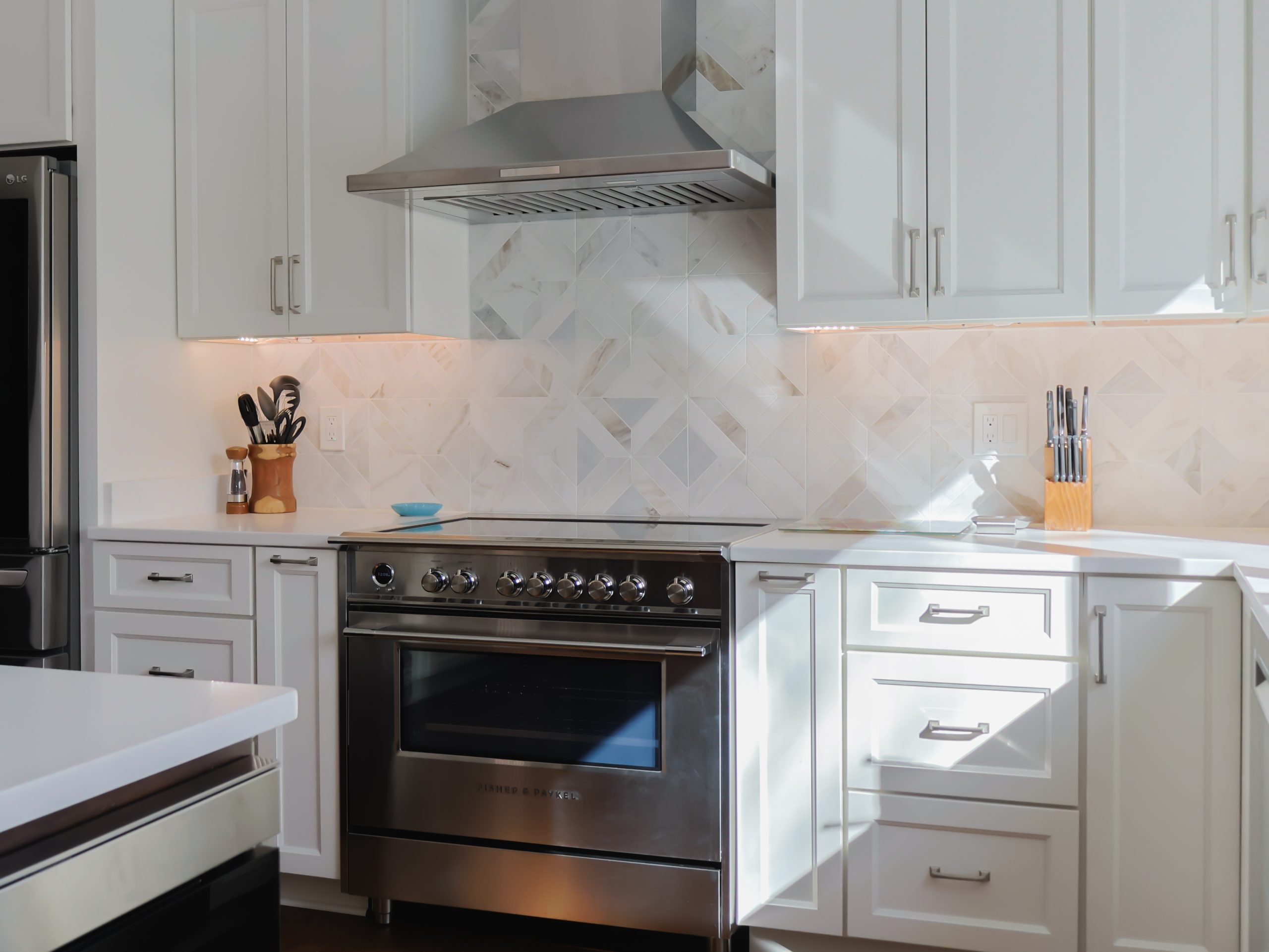 Bright white kitchen with shaker cabinets, quartz countertops, and range hood