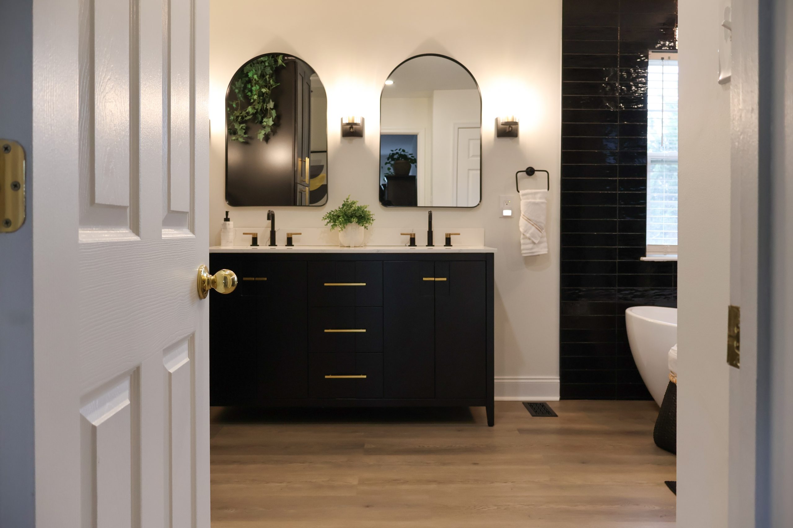 Dark bathroom vanity with double sinks and arched mirrors