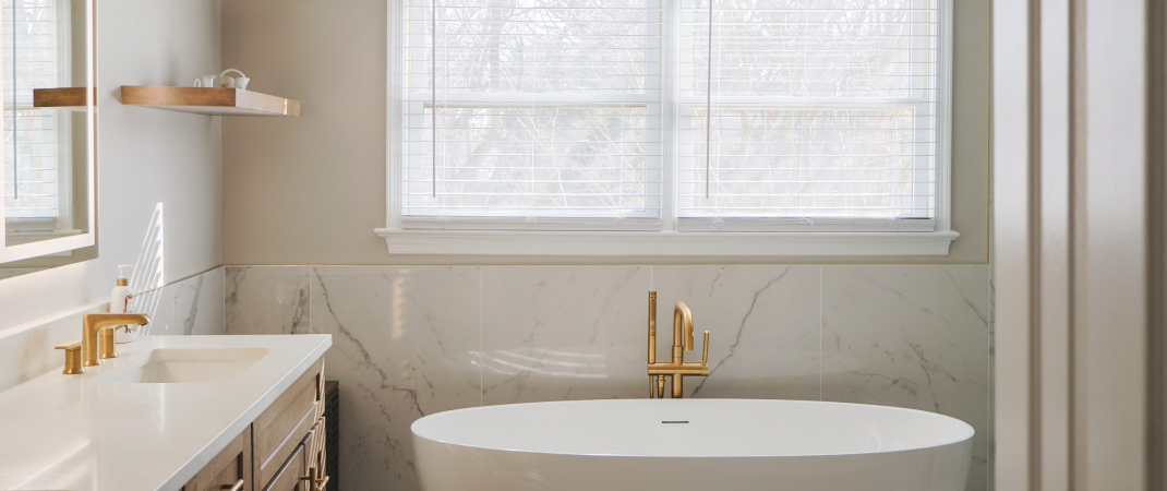 Modern bathroom in Ashburn, VA with gold-accented glass shower and soaking tub
